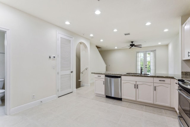 kitchen featuring dark stone counters, white cabinets, sink, ceiling fan, and appliances with stainless steel finishes