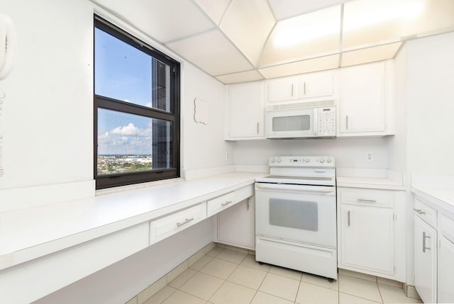 kitchen with white appliances, white cabinetry, and light tile patterned flooring