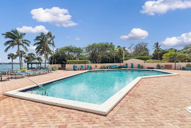 view of swimming pool with a patio area and a water view