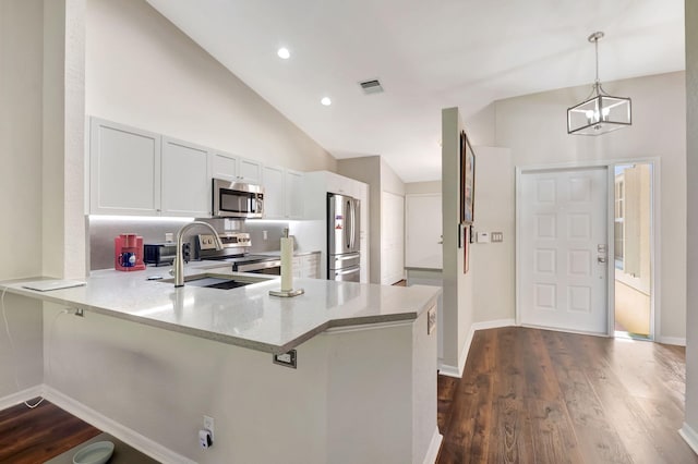 kitchen featuring kitchen peninsula, hanging light fixtures, dark hardwood / wood-style flooring, appliances with stainless steel finishes, and white cabinetry