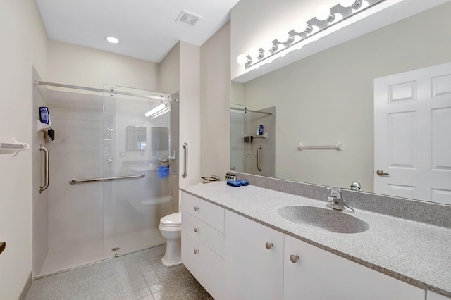 bathroom with a shower with door, vanity, toilet, and tile patterned flooring