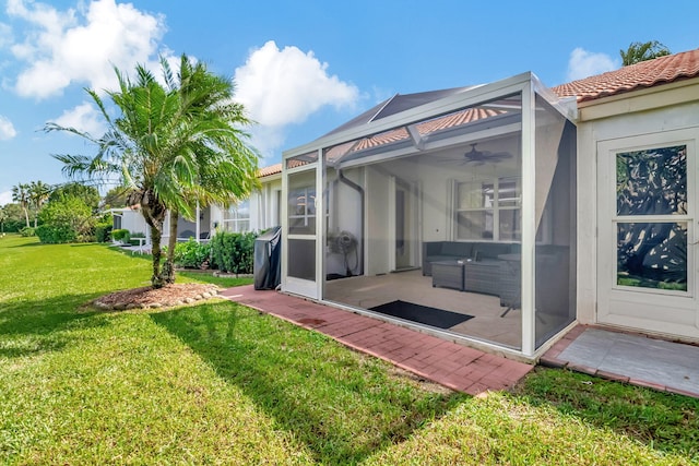 rear view of property featuring a patio, glass enclosure, a yard, and ceiling fan