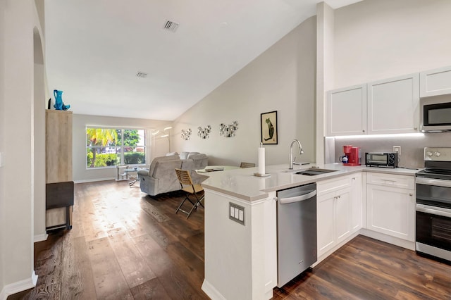 kitchen featuring stainless steel appliances, kitchen peninsula, dark hardwood / wood-style floors, and white cabinets