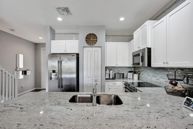 kitchen with white cabinetry, stainless steel appliances, and light stone counters