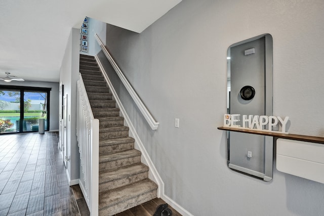 stairway with hardwood / wood-style floors and ceiling fan