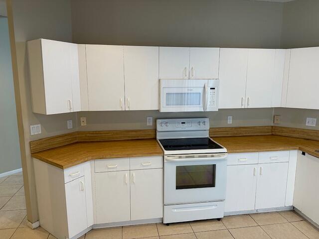 kitchen featuring white appliances, white cabinetry, and light tile patterned floors