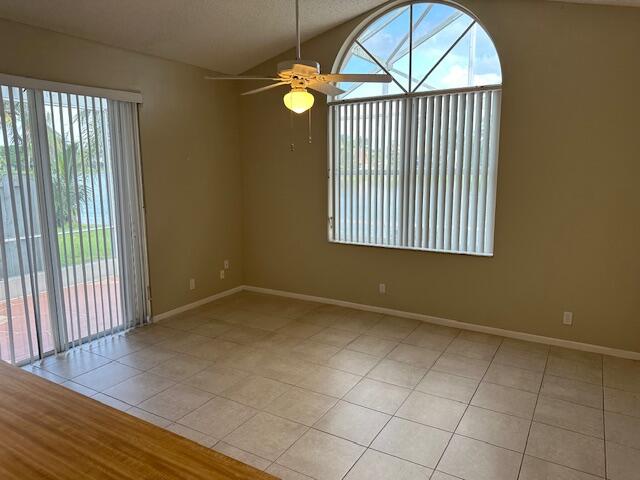 tiled empty room featuring lofted ceiling, a textured ceiling, and ceiling fan