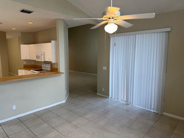 kitchen with white cabinets, ceiling fan, light tile patterned floors, and white appliances