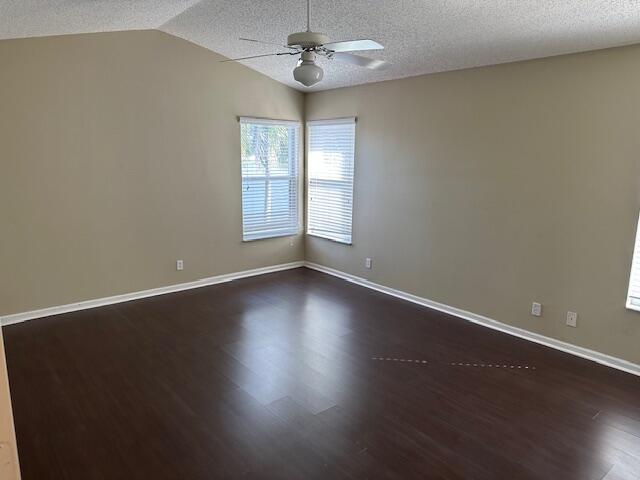 empty room with a textured ceiling, vaulted ceiling, and hardwood / wood-style floors