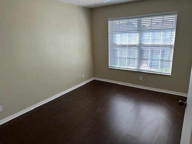 unfurnished room with dark wood-type flooring and ceiling fan