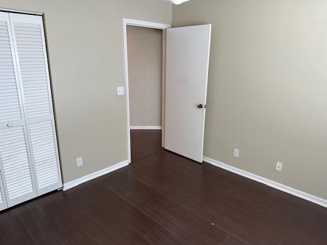 unfurnished bedroom with dark wood-type flooring and a closet