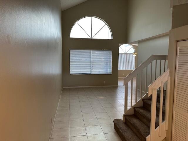 stairs with high vaulted ceiling and tile patterned flooring