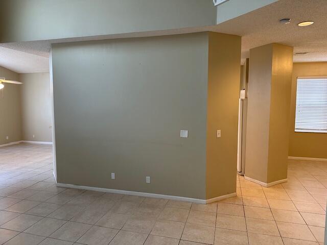 tiled spare room featuring a textured ceiling and ceiling fan