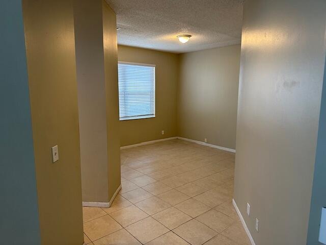 tiled empty room with a textured ceiling