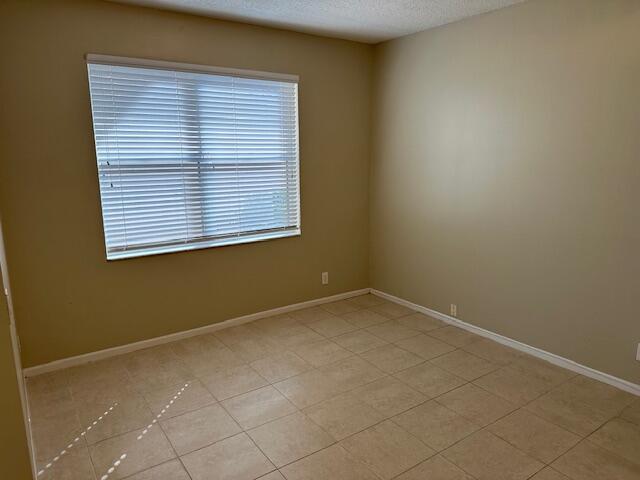 spare room featuring a textured ceiling and light tile patterned floors