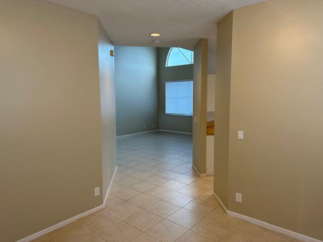 hall with a textured ceiling and light tile patterned floors