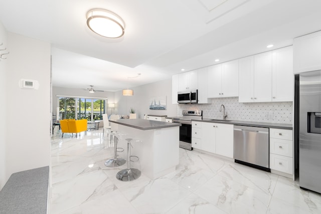 kitchen featuring tasteful backsplash, a center island, white cabinetry, stainless steel appliances, and a breakfast bar