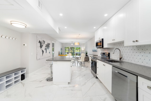 kitchen with sink, a center island, stainless steel appliances, white cabinets, and a breakfast bar