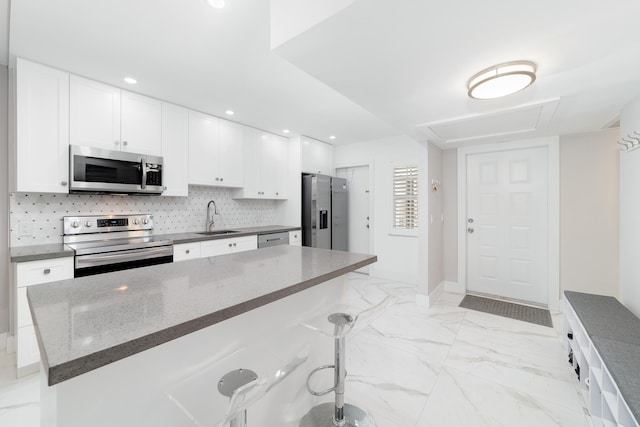 2801 N Palm Aire Dr Unit 106, Pompano Beach, FL 33069 - kitchen featuring a sink, stainless steel appliances, tasteful backsplash, a breakfast bar area, and white cabinets