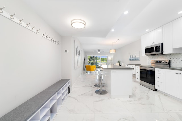 2801 N Palm Aire Dr Unit 106, Pompano Beach, FL 33069 - kitchen featuring dark countertops, a kitchen breakfast bar, white cabinets, appliances with stainless steel finishes, and decorative backsplash