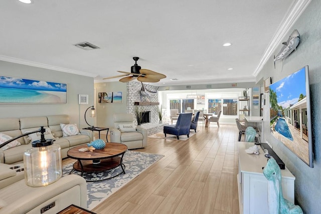 living room with a brick fireplace, ceiling fan, ornamental molding, and light wood-type flooring