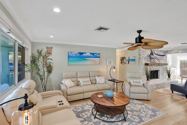 living room featuring light hardwood / wood-style flooring, a brick fireplace, ornamental molding, and ceiling fan