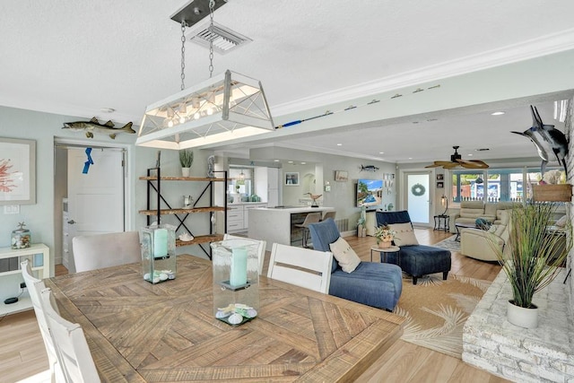 dining space with light hardwood / wood-style flooring, ceiling fan with notable chandelier, and ornamental molding