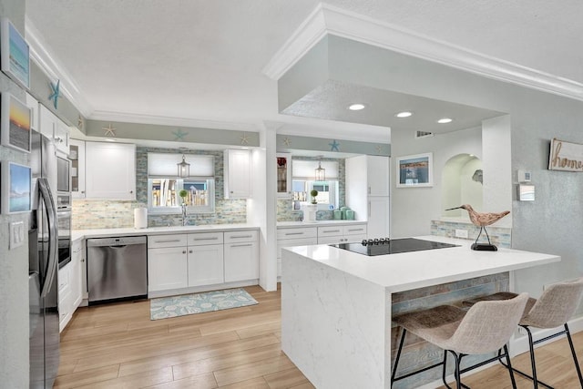 kitchen with a kitchen breakfast bar, white cabinets, light wood-type flooring, and stainless steel appliances