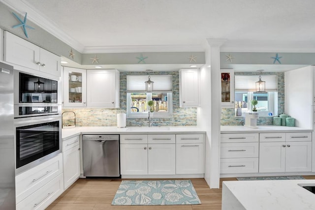 kitchen featuring decorative backsplash, appliances with stainless steel finishes, light wood-type flooring, ornamental molding, and white cabinets