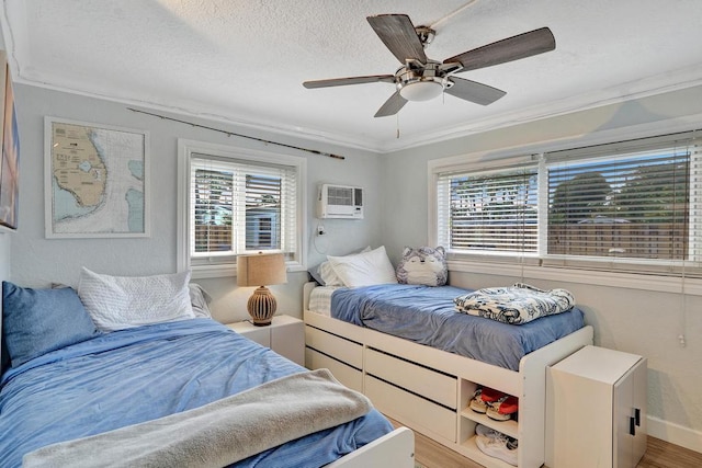 bedroom featuring multiple windows, a wall mounted AC, hardwood / wood-style flooring, and ceiling fan