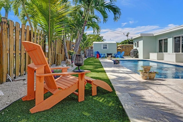 view of swimming pool featuring a lawn and a storage shed