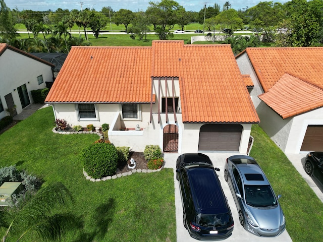 mediterranean / spanish home featuring a tiled roof, a garage, a front yard, and stucco siding