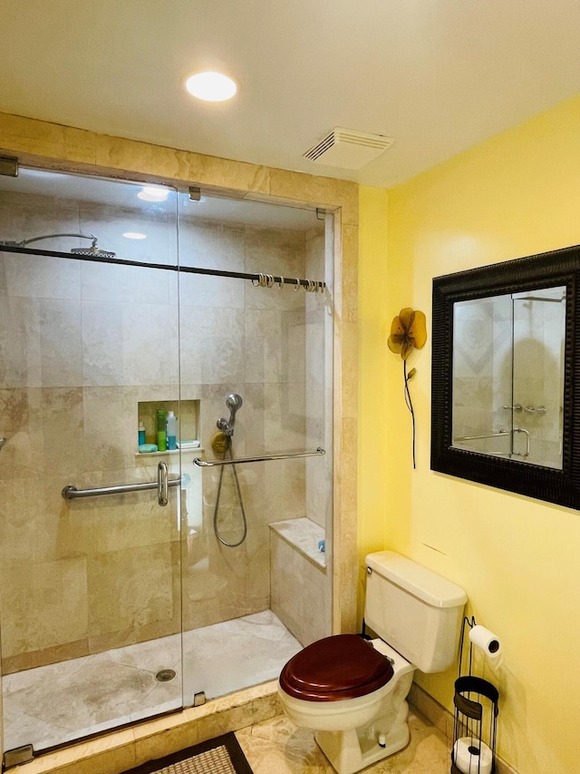 bathroom with tile patterned floors, toilet, and a shower with shower door