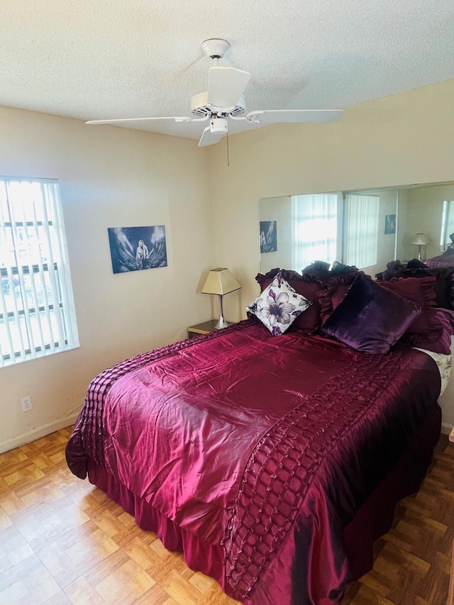 bedroom featuring ceiling fan, a textured ceiling, and multiple windows