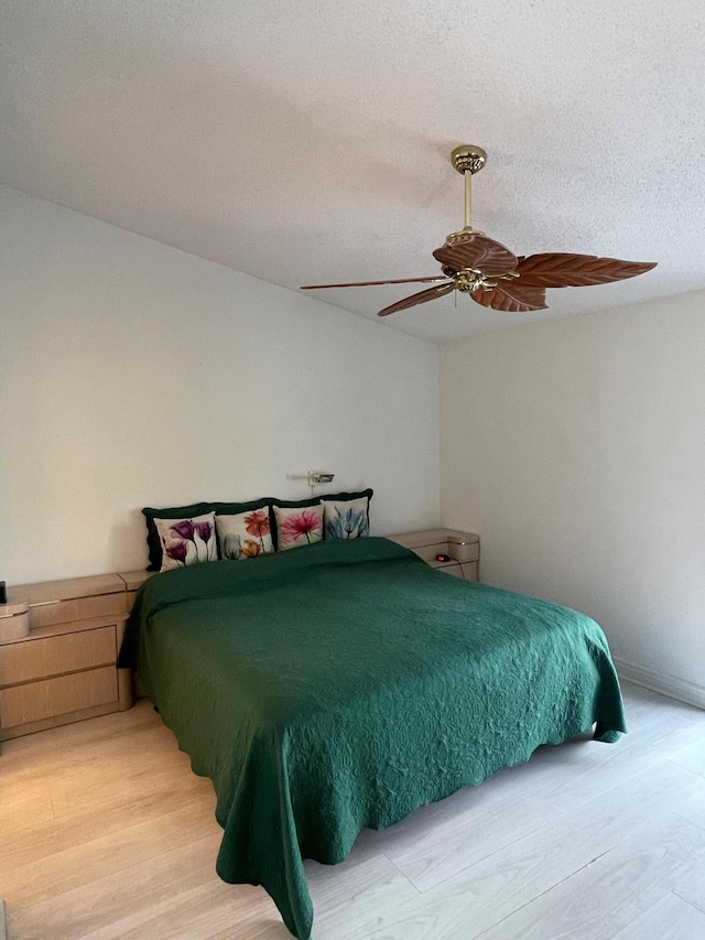 bedroom featuring ceiling fan, light wood-type flooring, and a textured ceiling