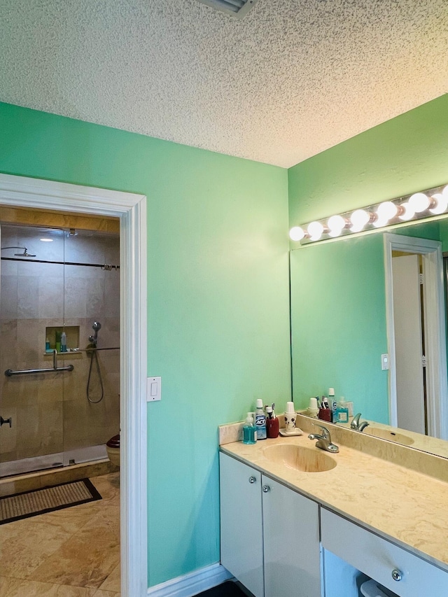 bathroom featuring vanity, a shower with shower door, a textured ceiling, and toilet