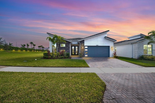 view of front of home with a garage and a lawn