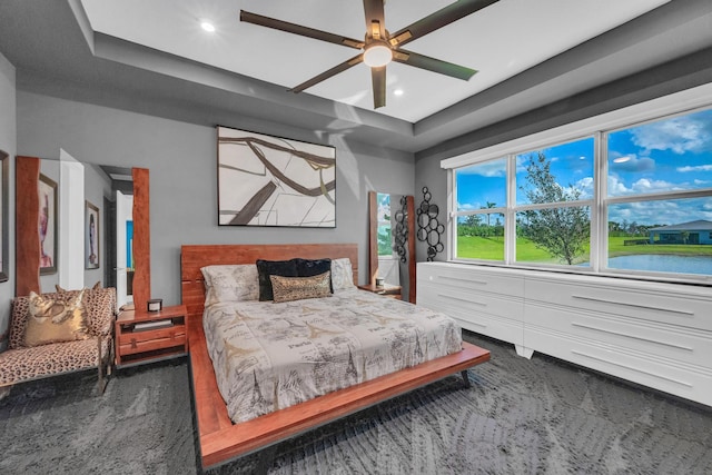 bedroom featuring a water view, ceiling fan, and a raised ceiling