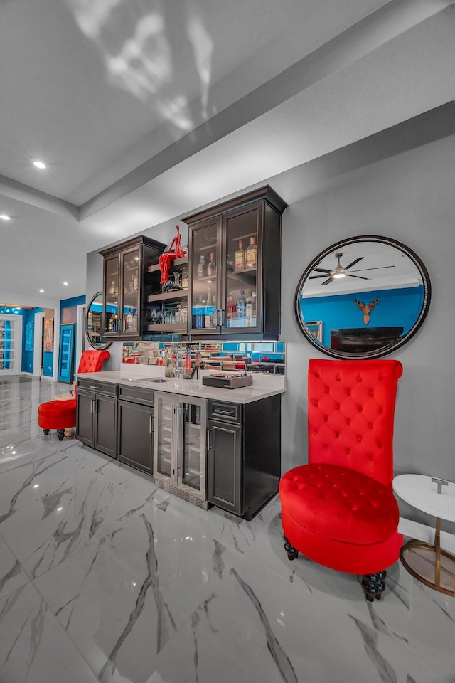 bar with dark brown cabinets, beverage cooler, and ceiling fan