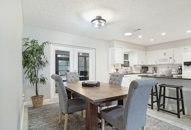 dining space with light tile patterned floors, a textured ceiling, sink, and french doors