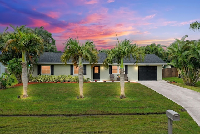 ranch-style house featuring a garage and a lawn