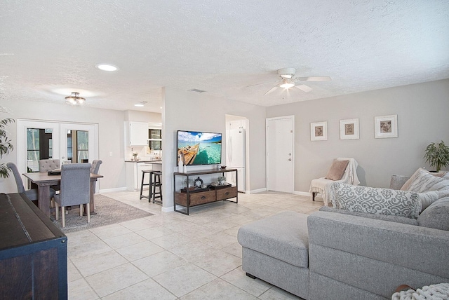 tiled living room featuring a textured ceiling, ceiling fan, and french doors