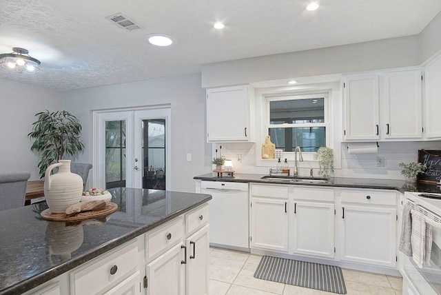 kitchen with white cabinets, sink, white appliances, and dark stone countertops