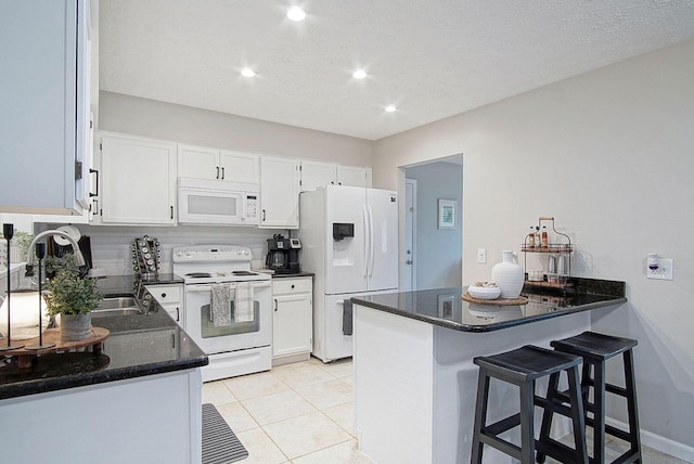 kitchen featuring white cabinetry, kitchen peninsula, sink, and white appliances