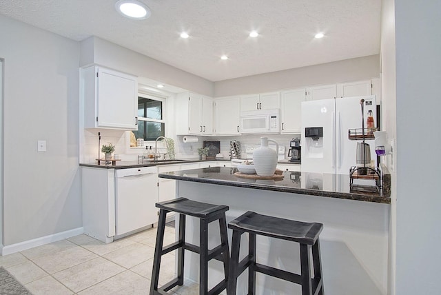 kitchen with backsplash, light tile patterned floors, sink, white cabinets, and white appliances