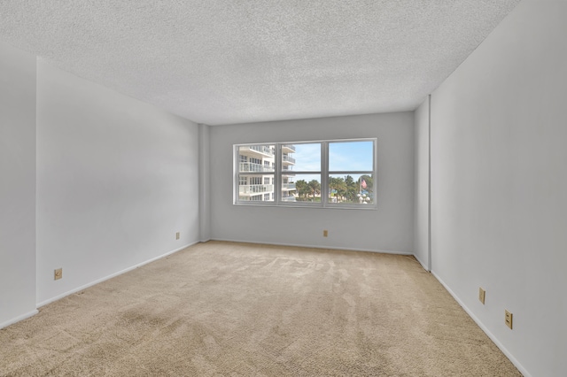 spare room featuring a textured ceiling and light colored carpet