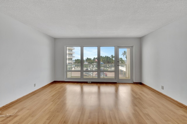 empty room with light hardwood / wood-style floors and a textured ceiling