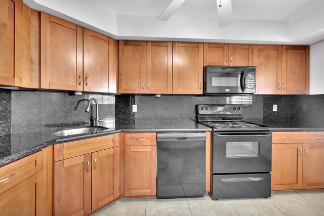 kitchen with decorative backsplash, dark stone countertops, black appliances, and sink