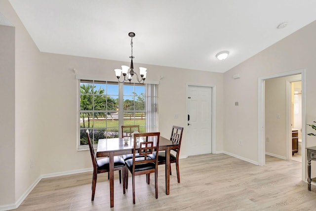 dining space with light hardwood / wood-style flooring, a notable chandelier, and vaulted ceiling