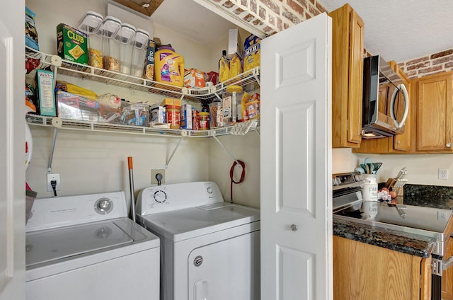 laundry area featuring brick wall and washer and dryer